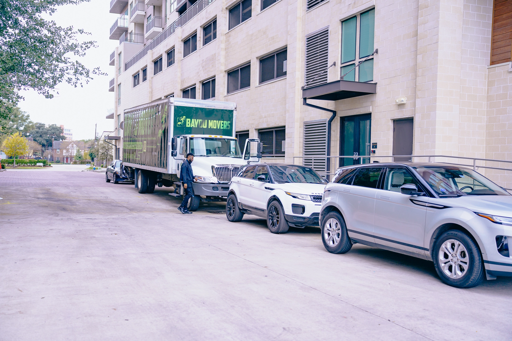 Bayou Movers truck staged beside a multi-story apartment building