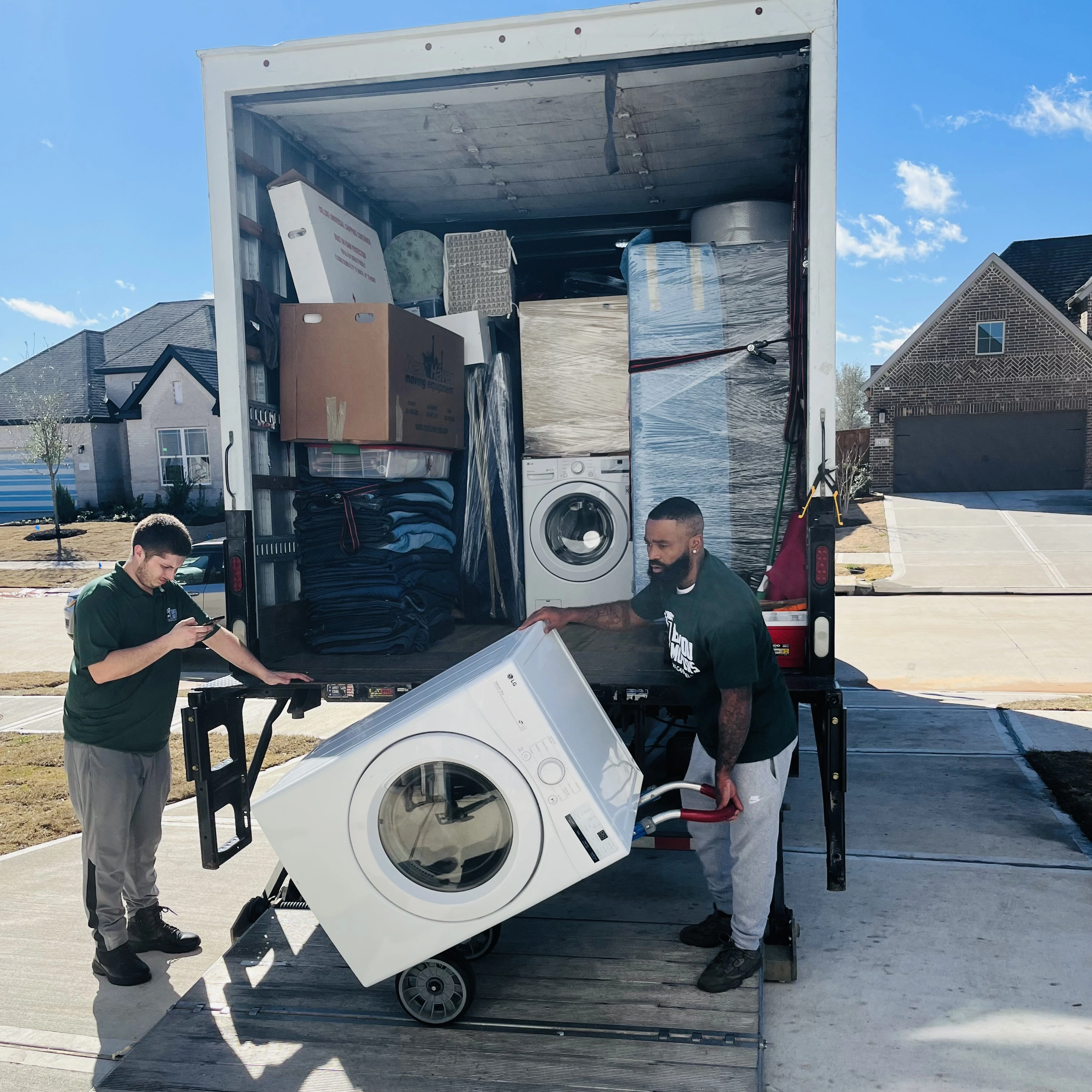 Two Bayou Movers crew members loading a washing machine