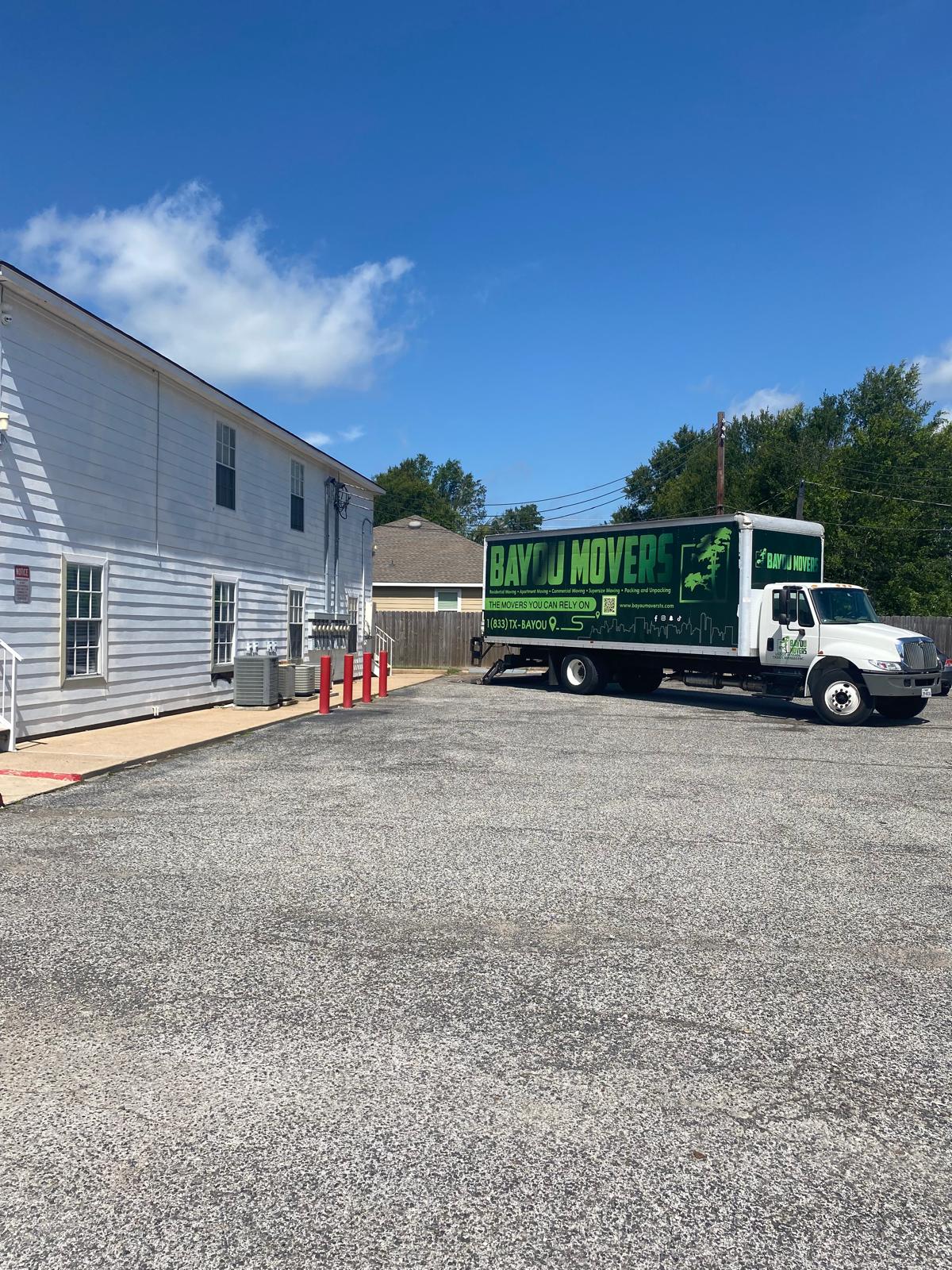 Bayou Movers truck staged beside a multi-unit property