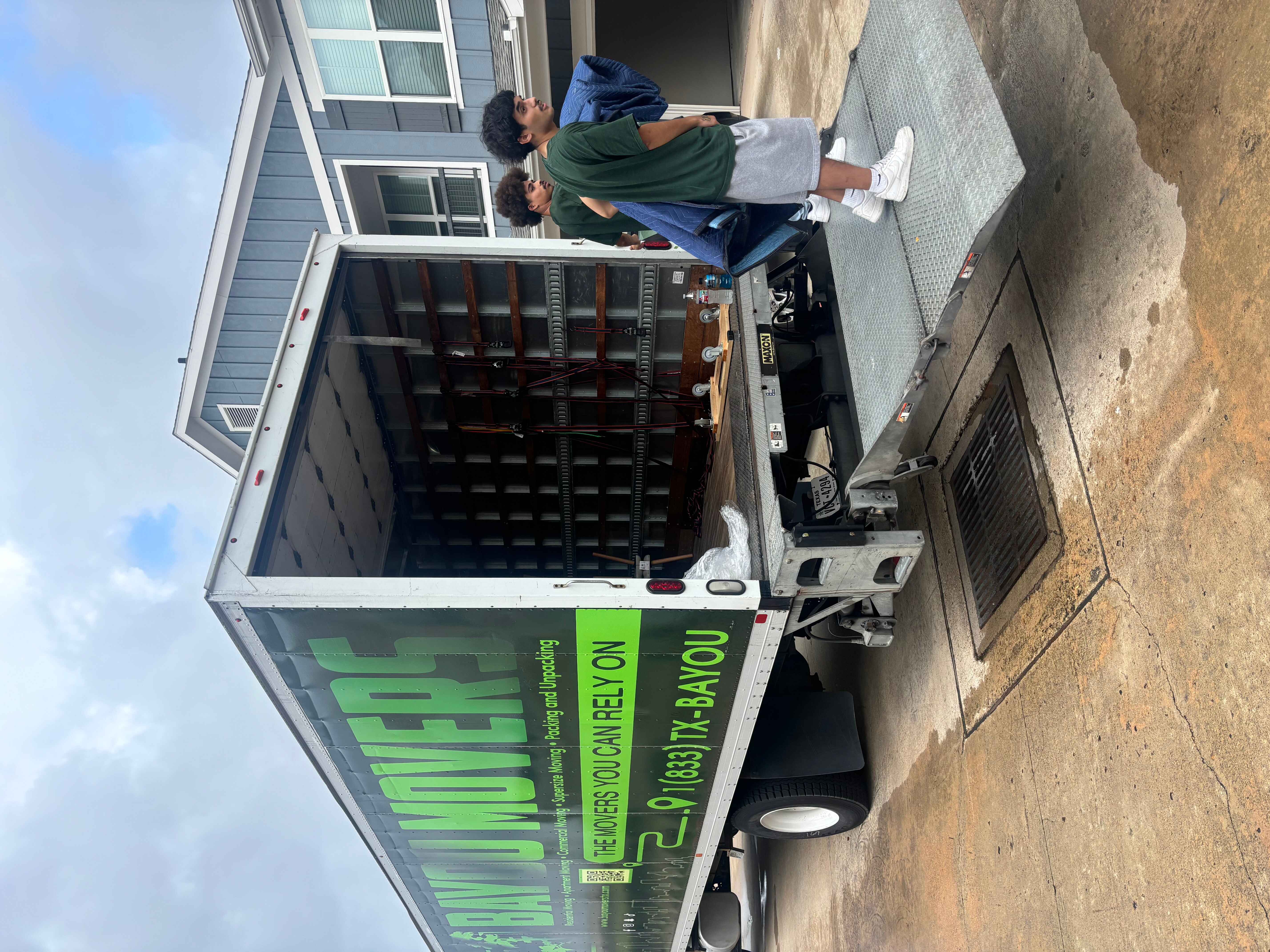 Two Bayou Movers crew members at an open truck liftgate