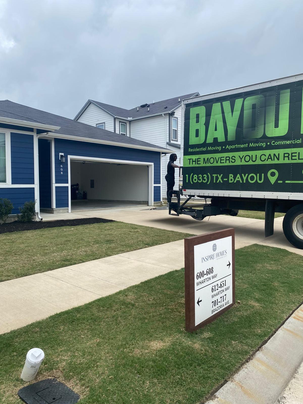 Bayou Movers truck parked beside an open residential garage